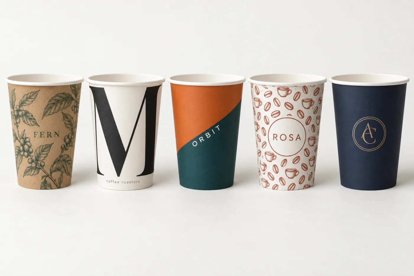 Five printed takeaway coffee cups in a row, each showing a different custom print style — botanical illustration on kraft, large editorial letterform, diagonal two-colour block, repeating pattern with a circular badge, and a fine line monogram on navy